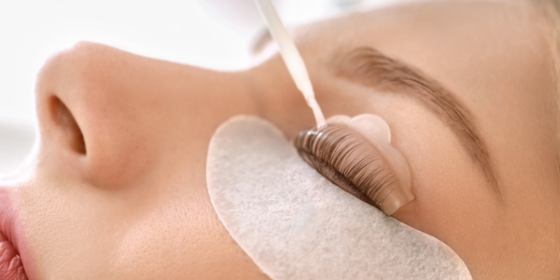 Young woman undergoing procedure of eyelashes lamination in beau